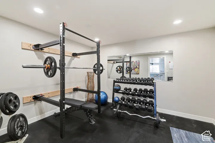 Dedicated fitness space featuring rubberized flooring, recessed lighting, and a wall-mounted mirror