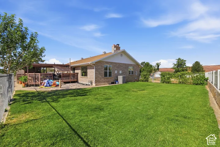 Expansive green lawn with a chain-link fence, stone retaining wall, and established plantings