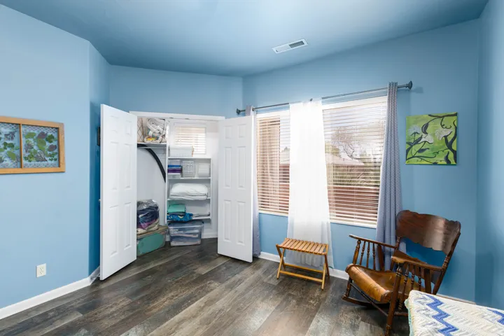 Interior room featuring wood-finish flooring, light blue walls, and a recessed ceiling vent