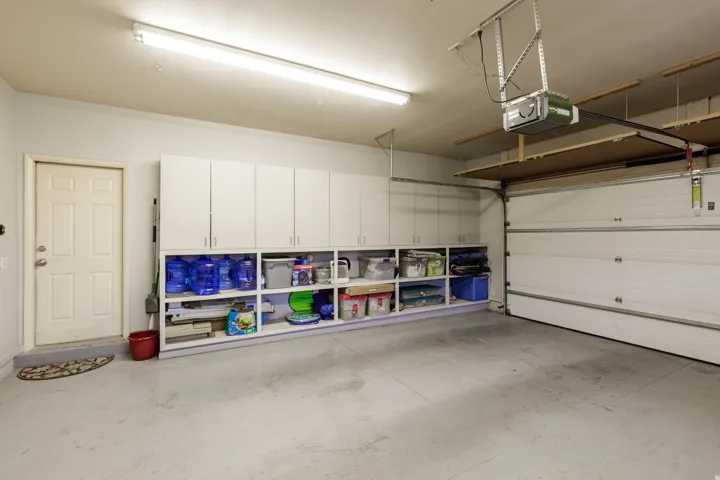 Spacious garage featuring extensive built-in cabinetry, open shelving, and a concrete floor