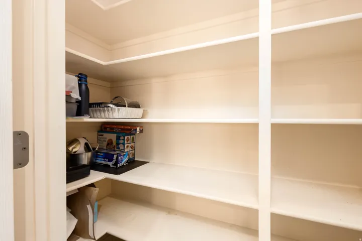 Walk-in pantry with extensive built-in shelving, white painted finishes, and a corner configuration