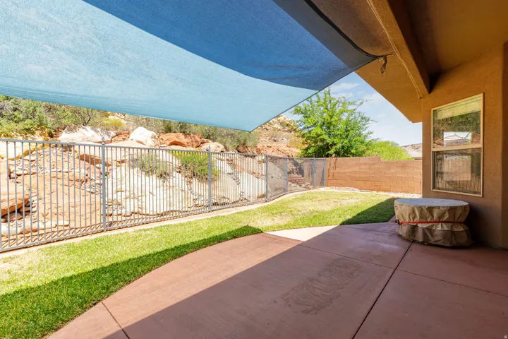 Patio featuring a sunshade, concrete surface, and a fenced yard with natural rock landscaping