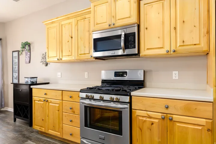 Kitchen featuring wood-finish cabinetry, light countertops, stainless steel gas range, and built-in microwave