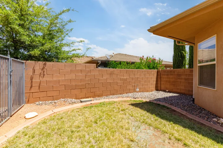 Private backyard with a block perimeter fence, gravel landscaping, and a grass area