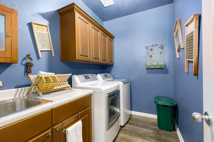 Laundry room featuring a built-in sink, wood-finish cabinetry, and wood-finish flooring