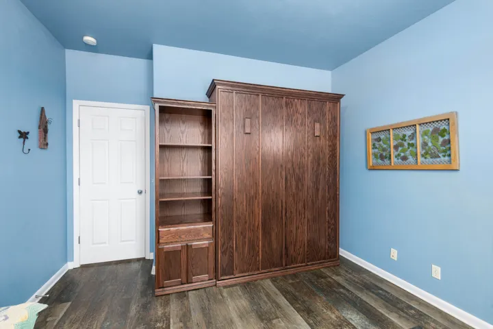 Built-in wood-finish cabinetry featuring a full-height unit with storage, a five-shelf bookcase, and a lower two-door cabinet