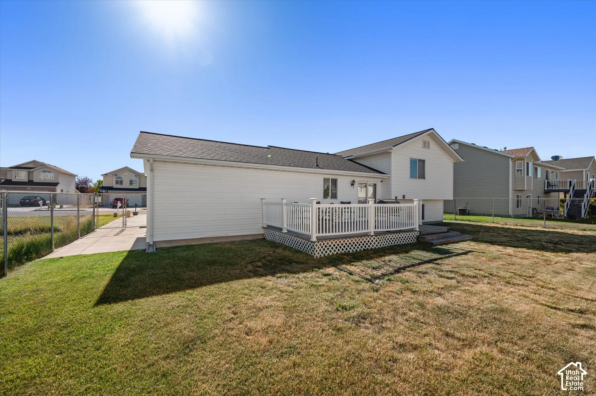Expansive backyard featuring a white vinyl deck with lattice skirting and a privacy railing