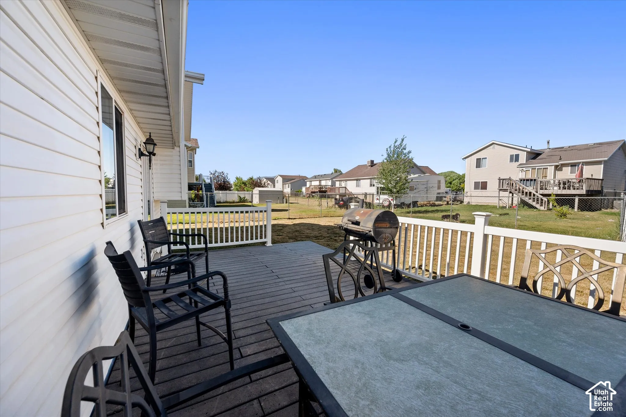 Spacious wood-finish deck with white railings extending along the rear of the property