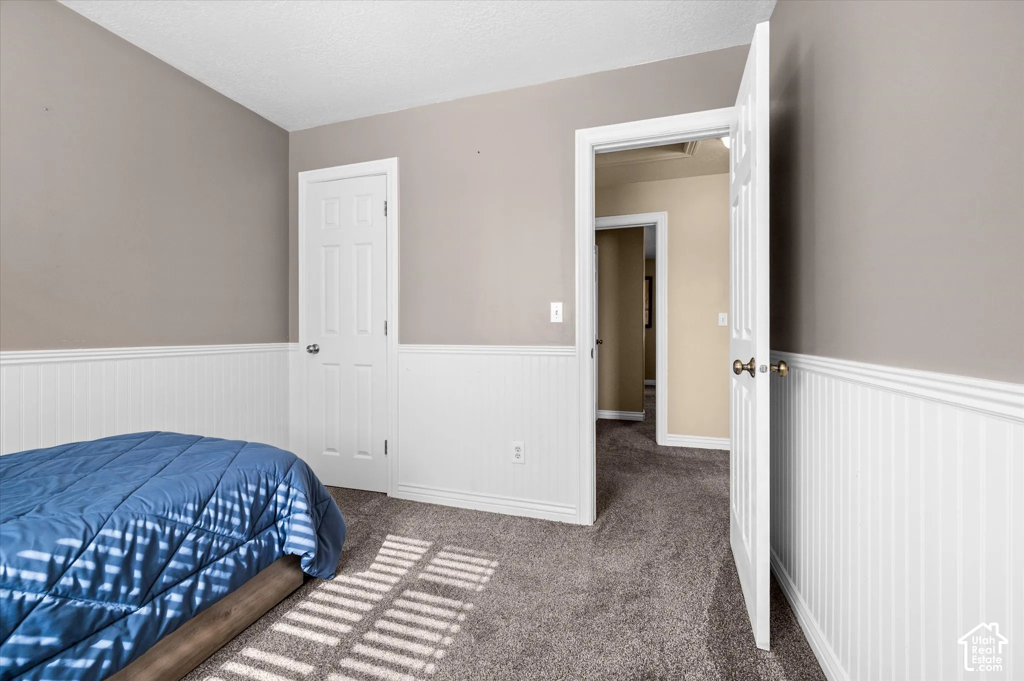Interior room featuring neutral paint, white wainscoting, and gray carpet flooring