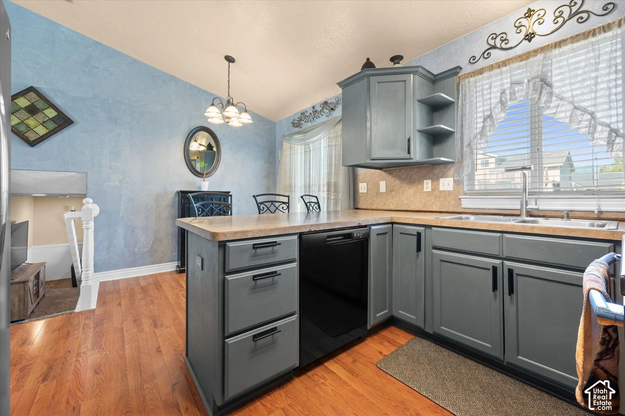 Kitchen featuring slate-toned cabinetry, light-toned countertops, and wood-finish flooring