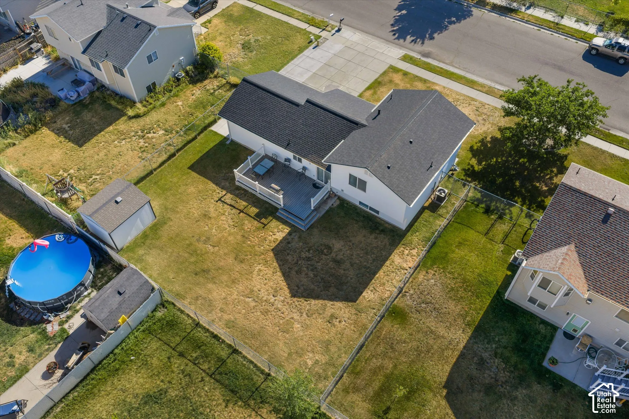 Spacious backyard featuring a multi-level deck, two storage sheds, and full perimeter fencing