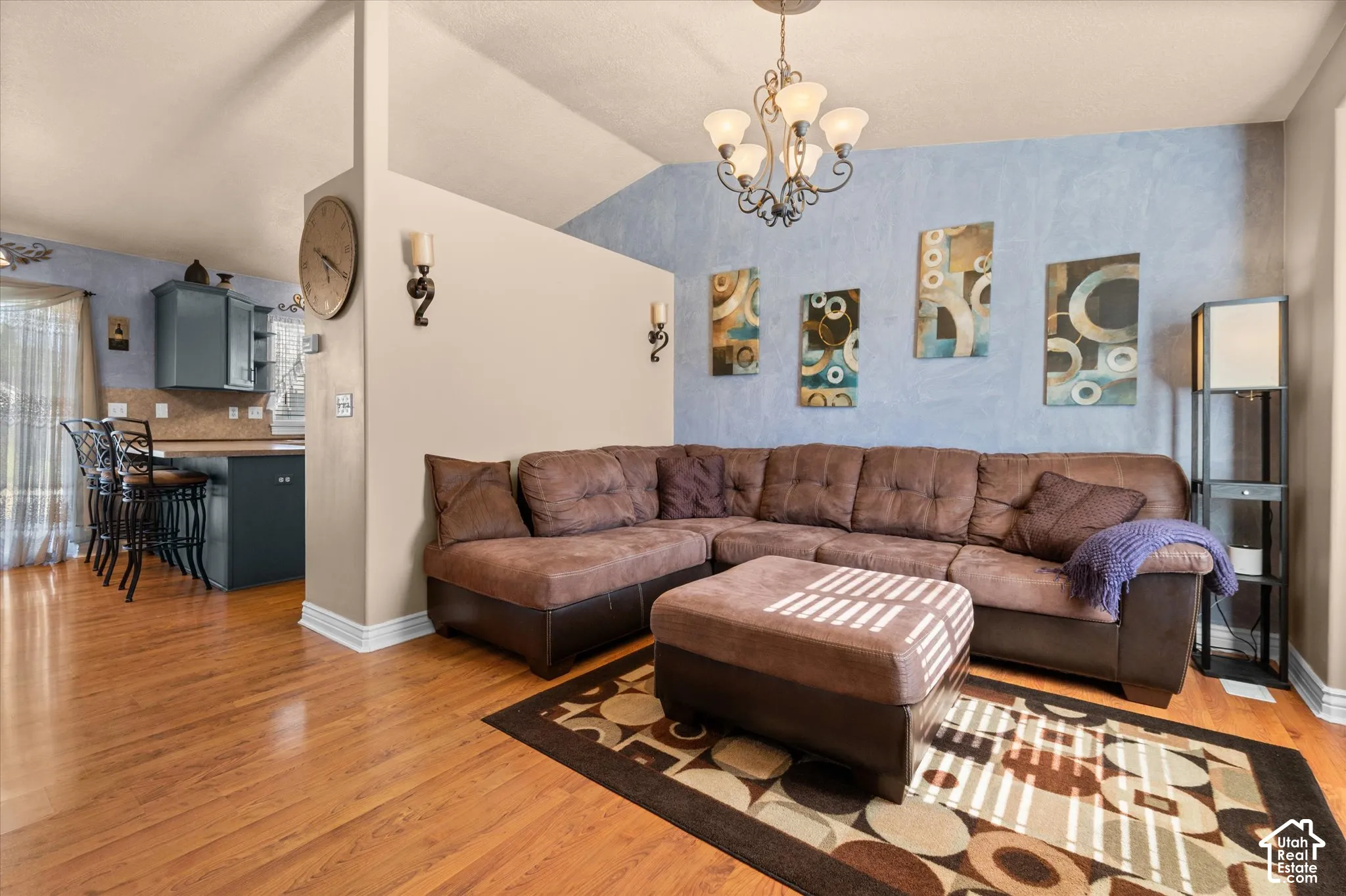 Living area featuring wood-finish flooring, a partial wall, and a vaulted ceiling