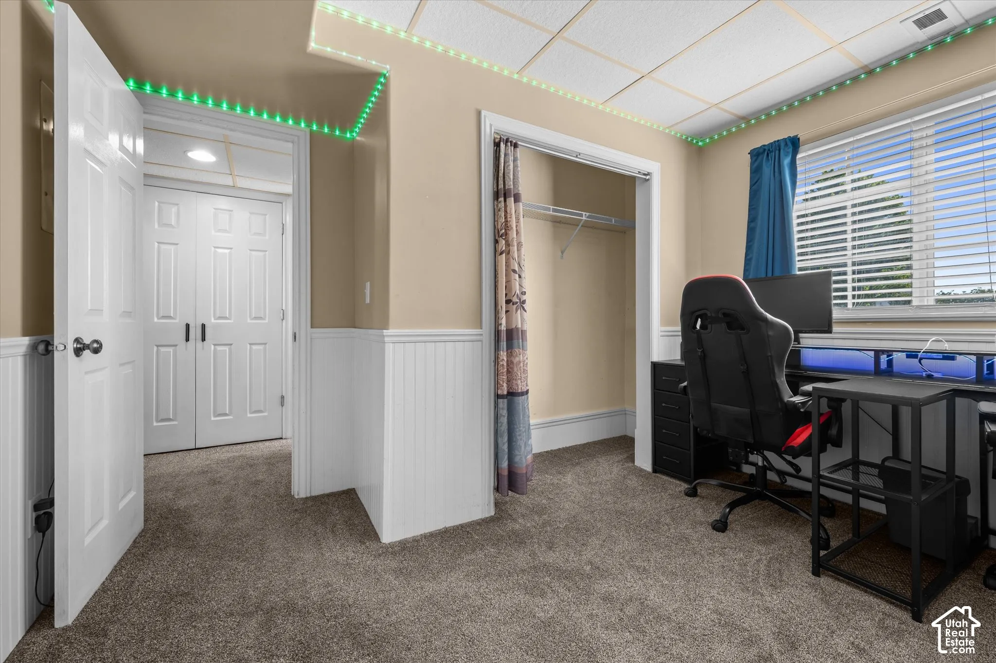 Interior space featuring wall-to-wall carpeting, white beadboard wainscoting, and a drop ceiling