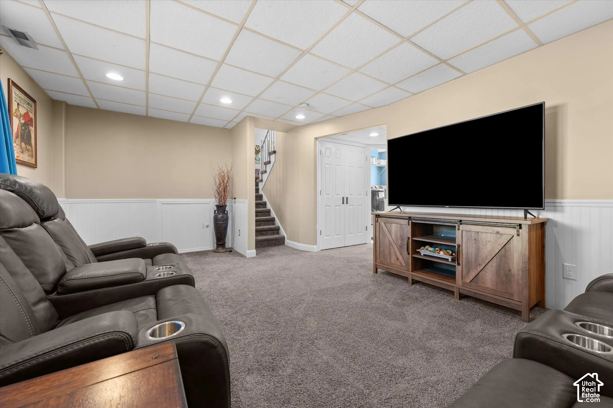 Carpeted lower-level room featuring light beige walls and white wainscoting