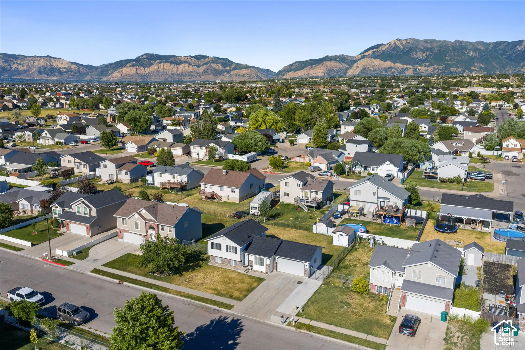 Aerial perspective showcasing a residential area with diverse home styles, paved streets, and mountainous terrain in the background