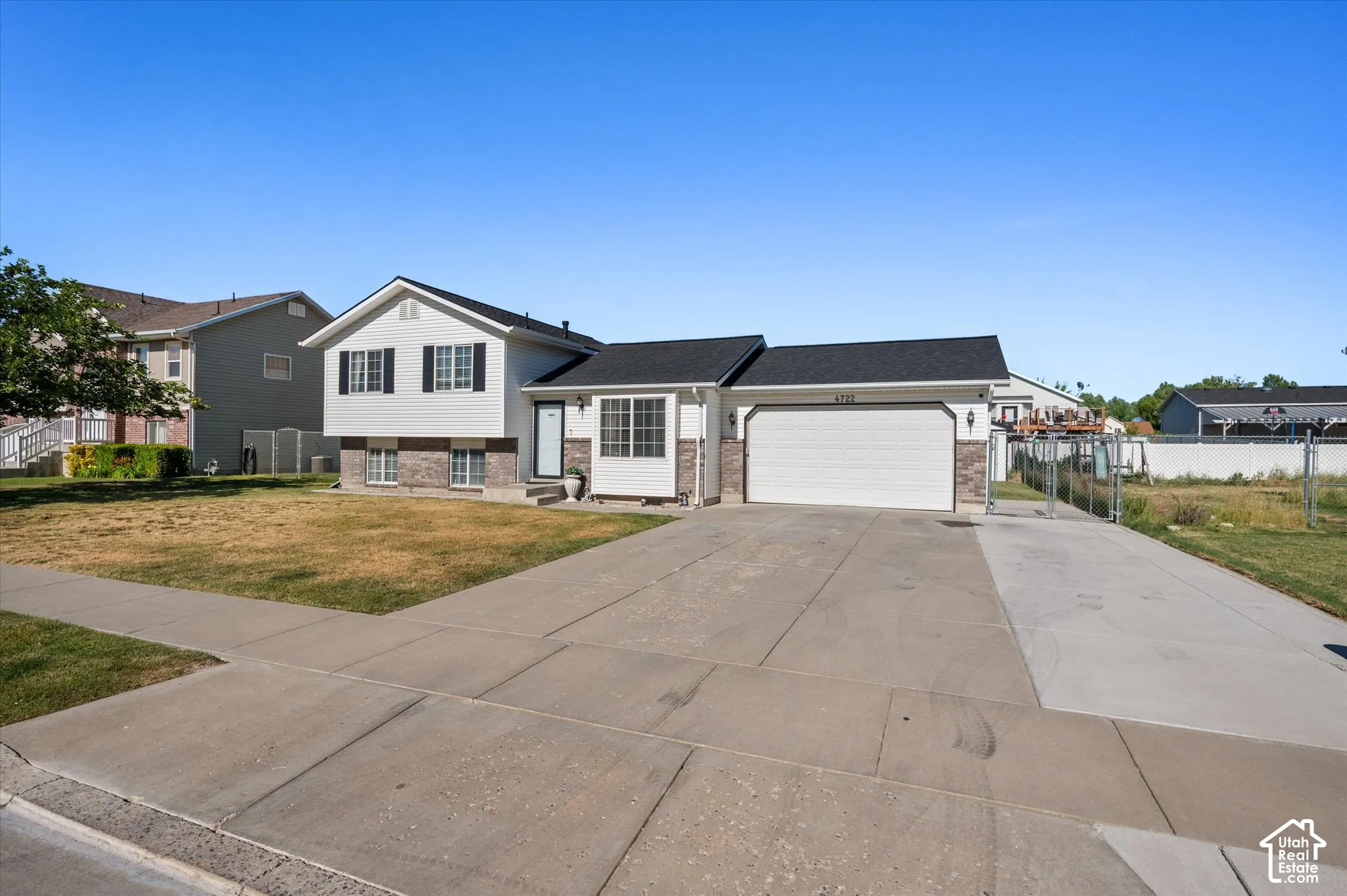 Split-level residence featuring white siding and dark shingle roofing