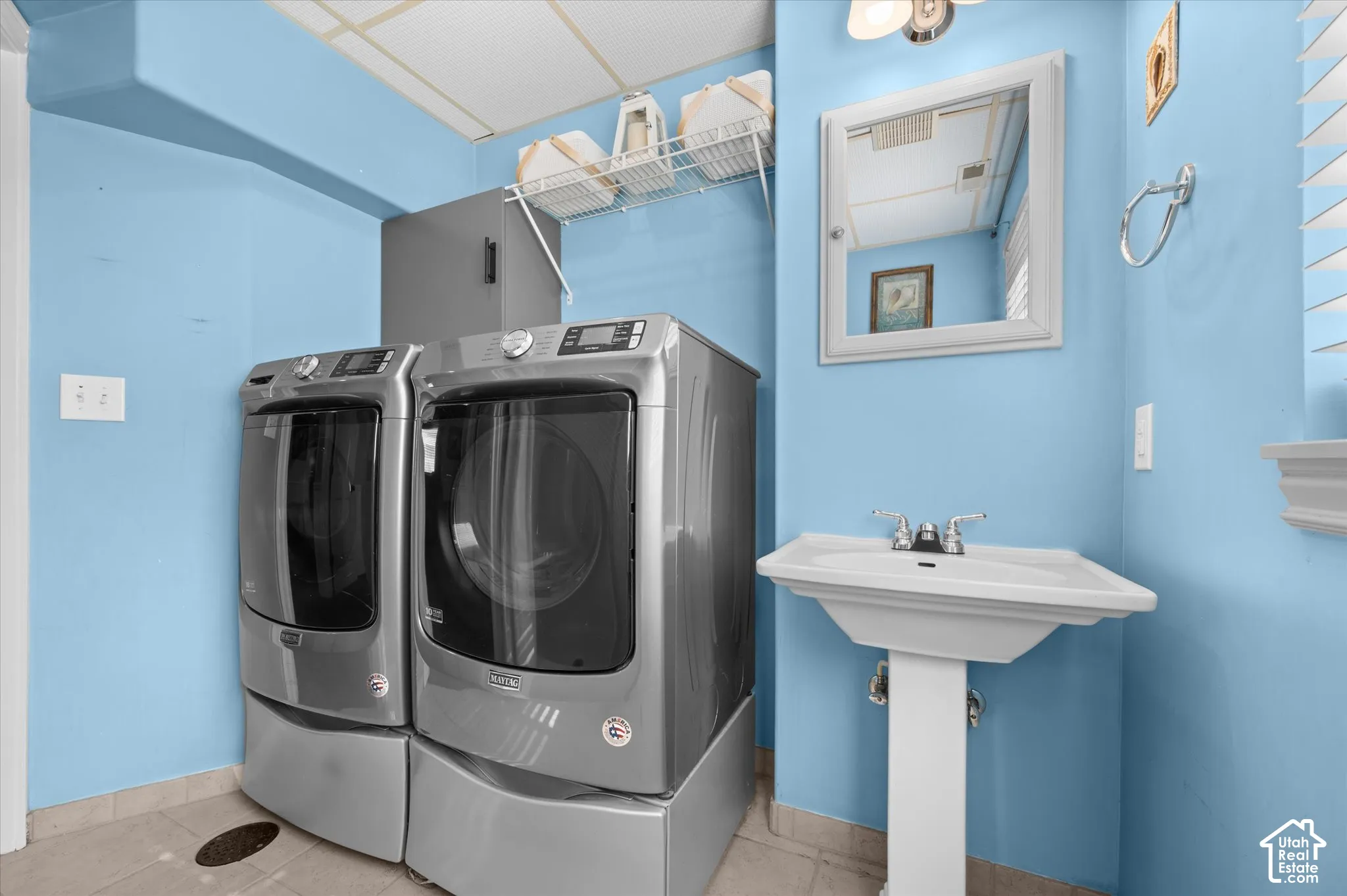 Dedicated laundry area featuring a pedestal sink, wall-mounted medicine cabinet, and tile flooring