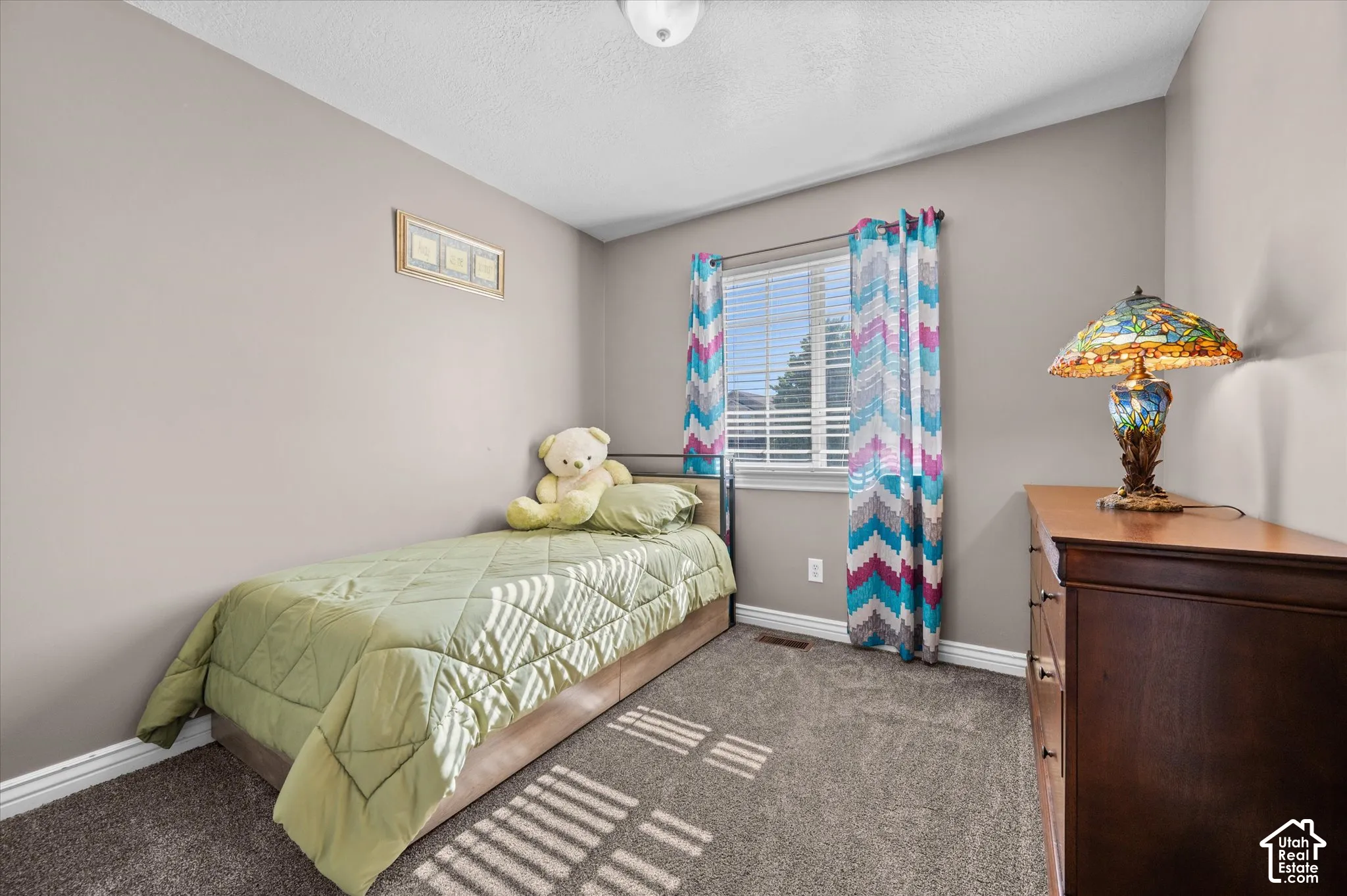 Gray wall paint with white trim, a single window featuring horizontal blinds, and dark gray carpet flooring