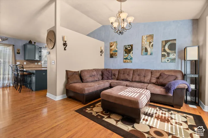 Living area featuring wood-finish flooring, a partial wall, and a vaulted ceiling