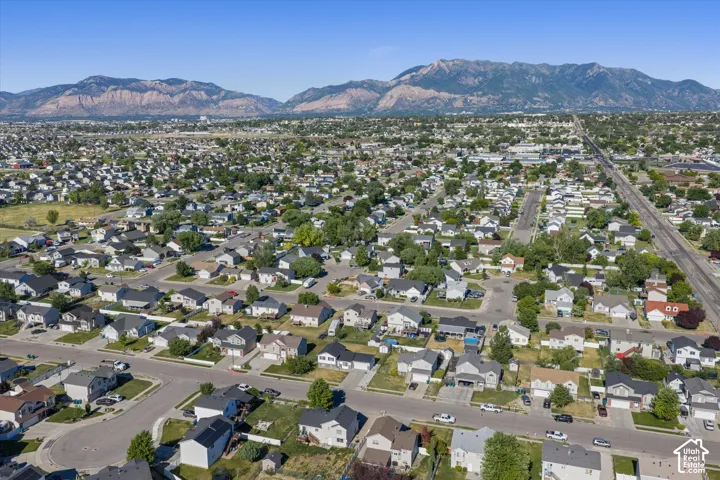 Residential area with mountain backdrop, featuring single-family homes, mature trees, and paved roads