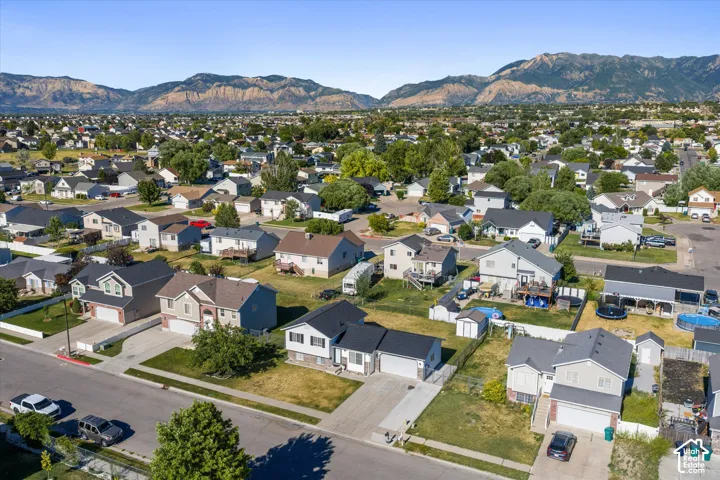 Aerial perspective showcasing a residential area with diverse home styles, paved streets, and mountainous terrain in the background