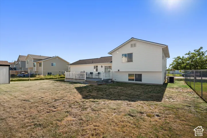 Expansive backyard featuring a multi-level deck, white vinyl siding, a storage shed, and a chain-link fence