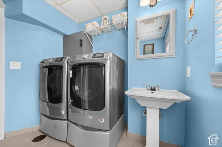Dedicated laundry area featuring a pedestal sink, wall-mounted medicine cabinet, and tile flooring