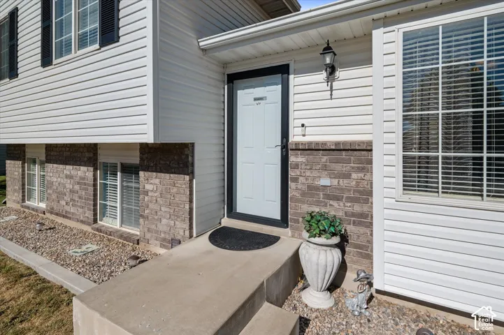 Exterior featuring white siding, brick veneer, and a white front door with a black storm door