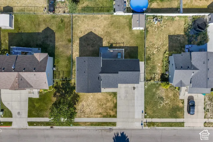 Property featuring a dark shingle roof, a two-car concrete driveway, a concrete sidewalk, and a fenced backyard
