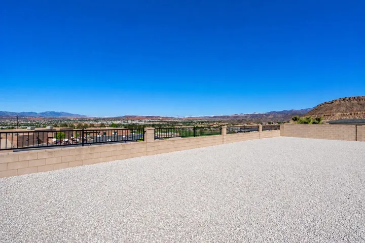Expansive outdoor gravel area featuring a block retaining wall with black metal railing