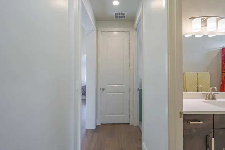 Hallway featuring wood-finish flooring, white walls, and recessed lighting