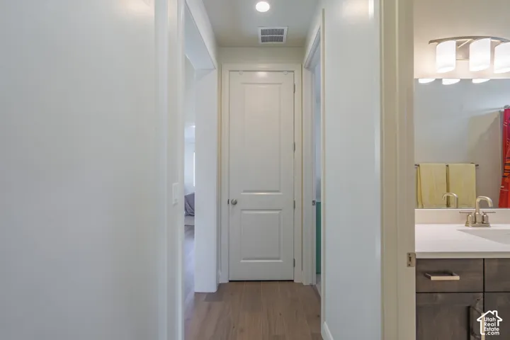 Hallway featuring wood-finish flooring, white walls, and recessed lighting