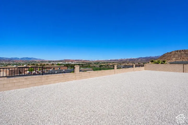 Expansive outdoor gravel area featuring a block retaining wall with black metal railing