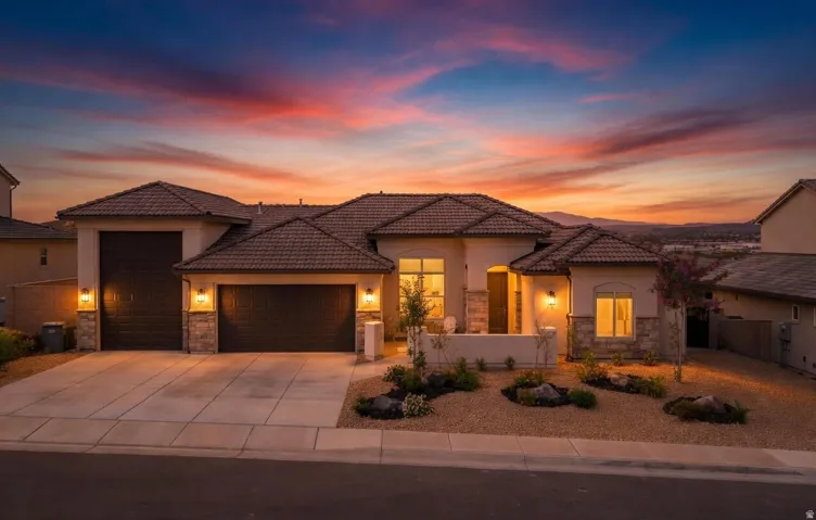 Southwestern-style residence featuring a tile roof, stucco exterior with stone accents, a two-car garage, and desert landscaping with decorative rocks