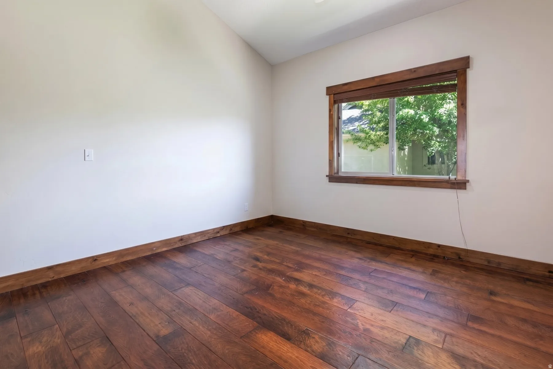 Room featuring wood-finish flooring and a window with wood trim