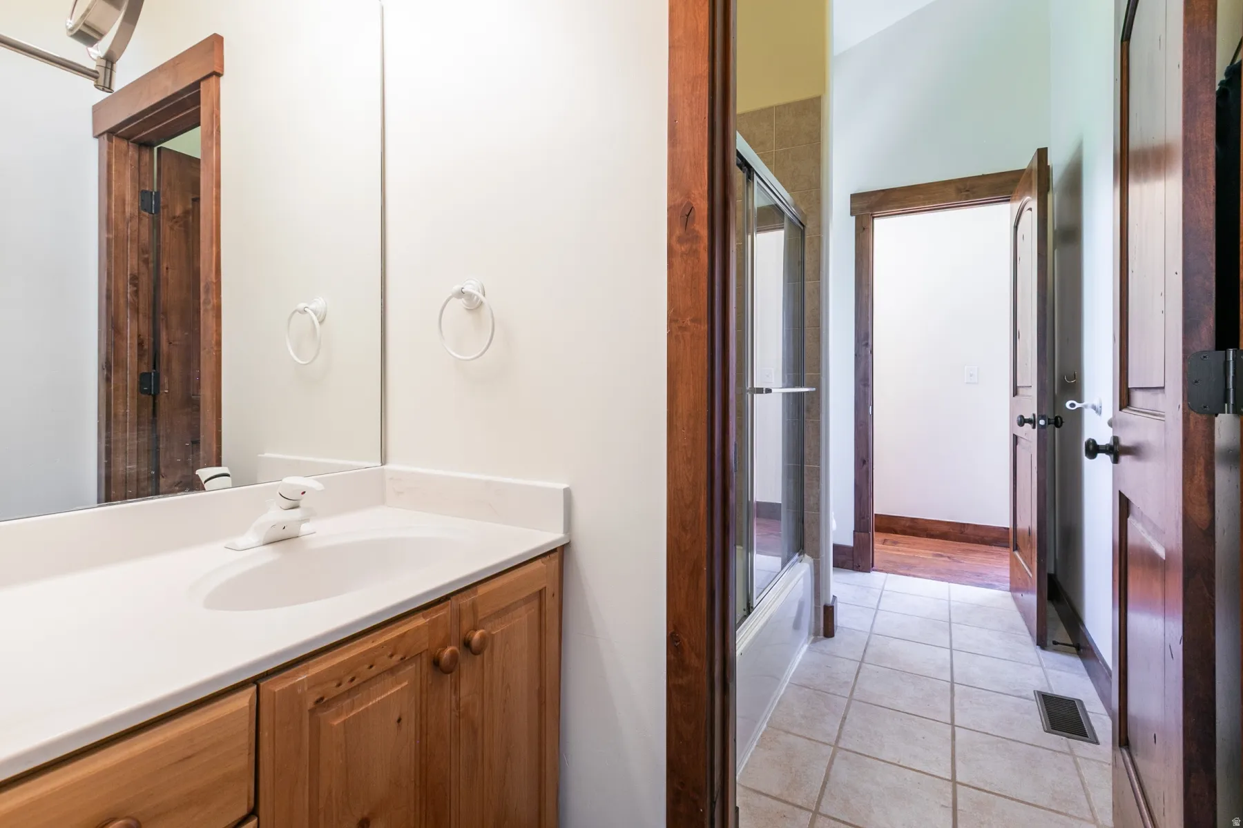 Bathroom vanity featuring a white countertop with an integrated sink, wood cabinetry, and a framed mirror