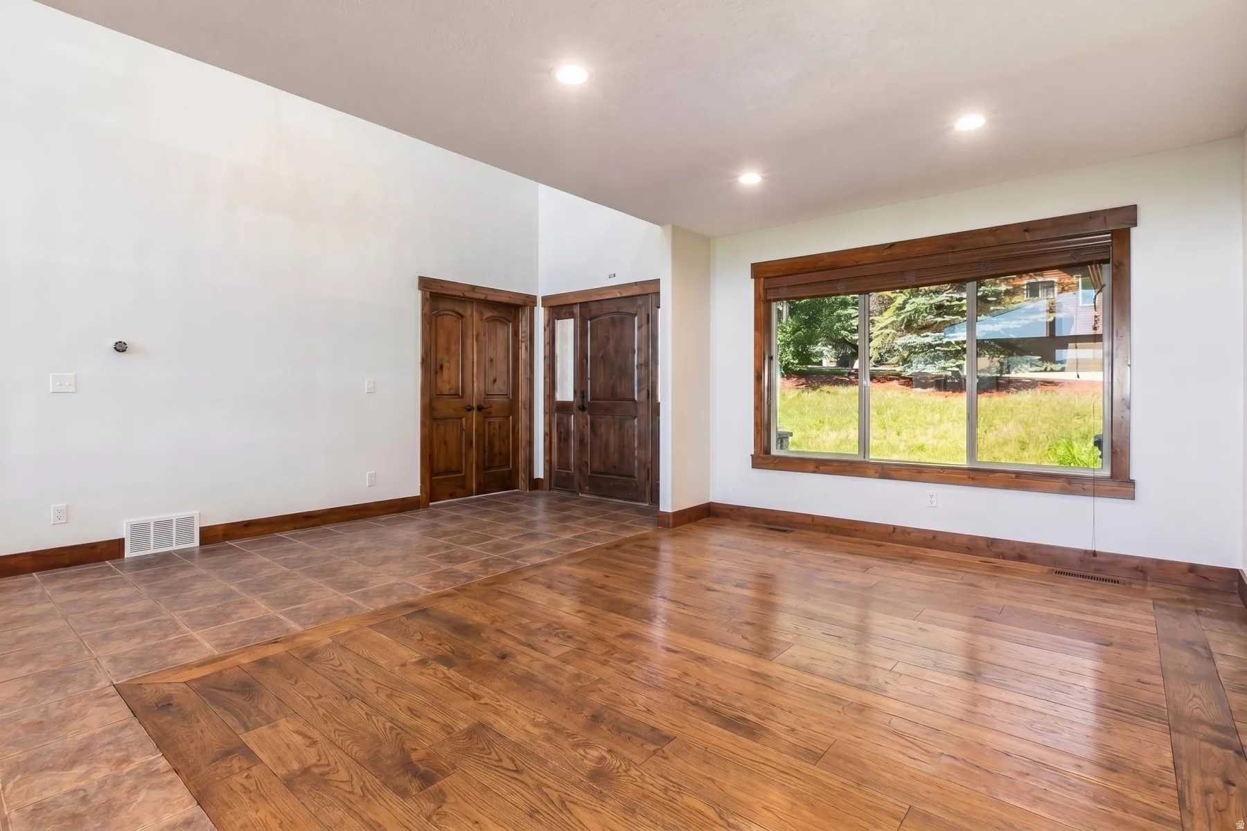 Spacious room featuring wood-finish flooring, recessed lighting, and a large window with wood trim