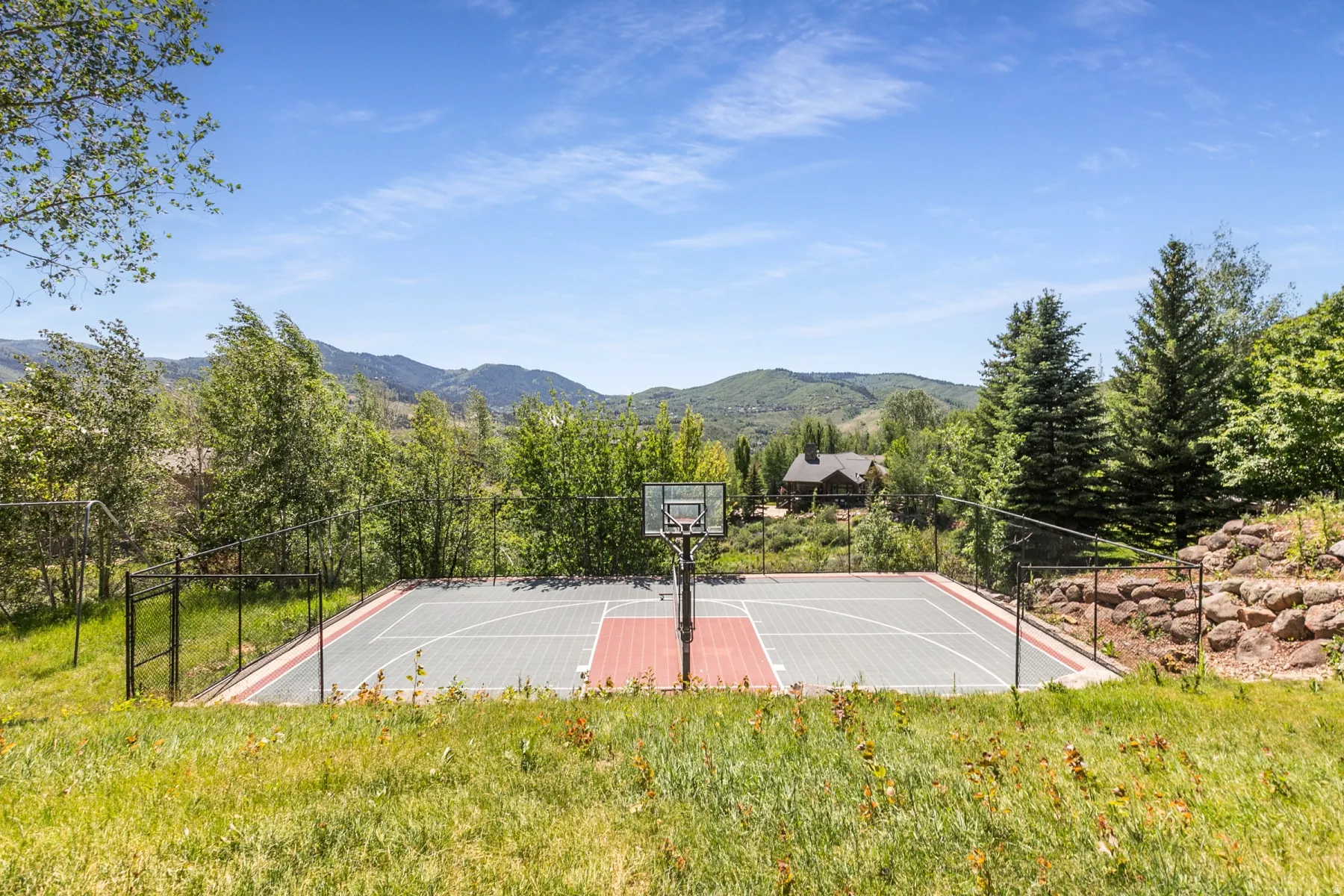 Fenced outdoor multi-sport court with a basketball hoop