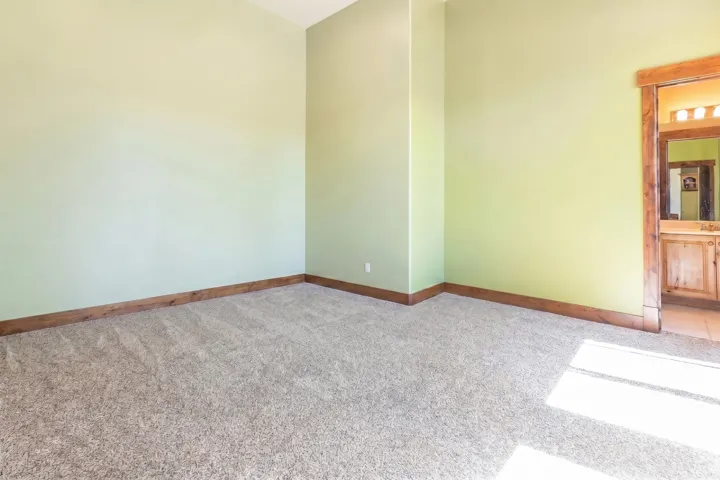 Carpeted room with light green walls and wood-finish baseboards