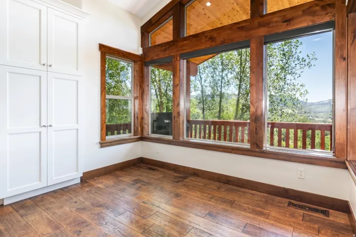Room with wood-finish flooring, white walls, and built-in white cabinetry