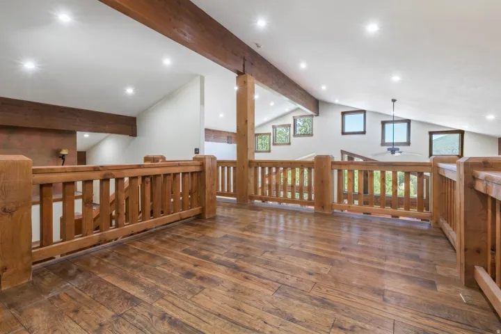 Wood-finish flooring throughout an open loft area with natural wood railings