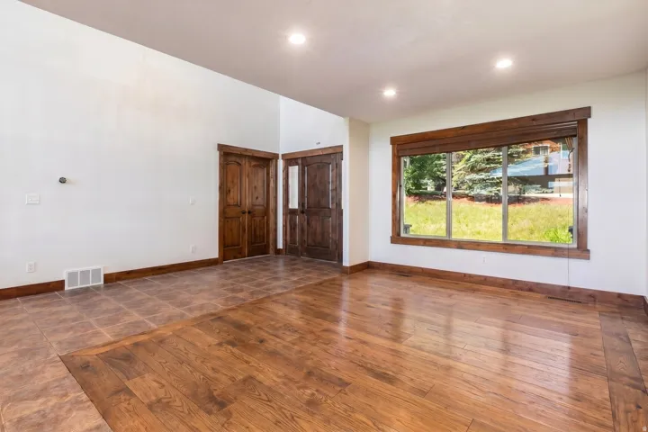 Spacious room featuring wood-finish flooring, recessed lighting, and a large window with wood trim