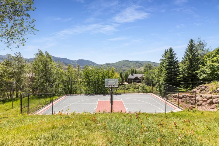 Fenced outdoor multi-sport court with a basketball hoop