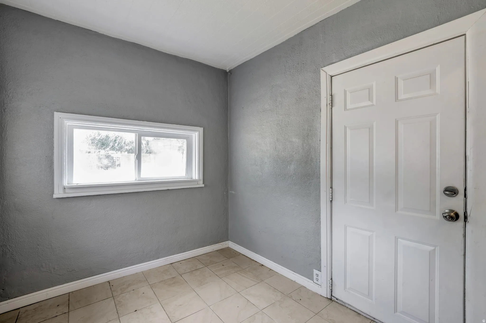 Room featuring neutral gray walls and light-toned floor tiling