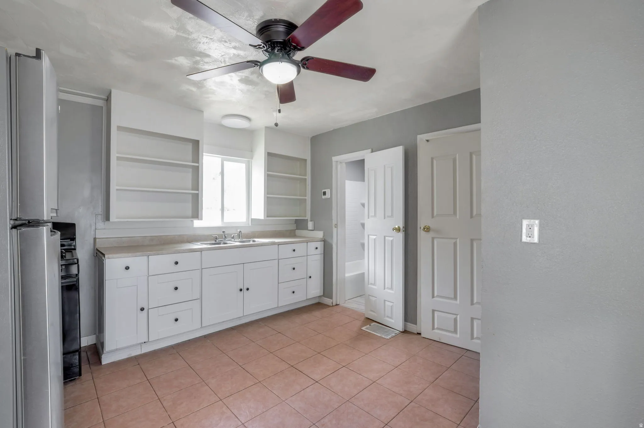 Kitchen featuring white cabinetry, light-toned countertops, and a stainless steel refrigerator
