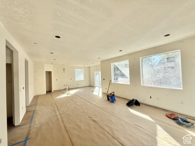 Spacious interior with large windows providing natural light, recessed lighting, and wall-to-wall flooring protection