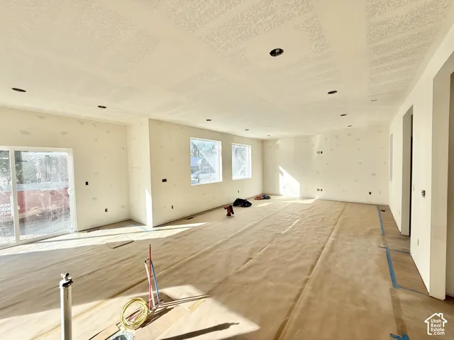 Expansive room with multiple windows, recessed ceiling lighting, and a sliding glass door