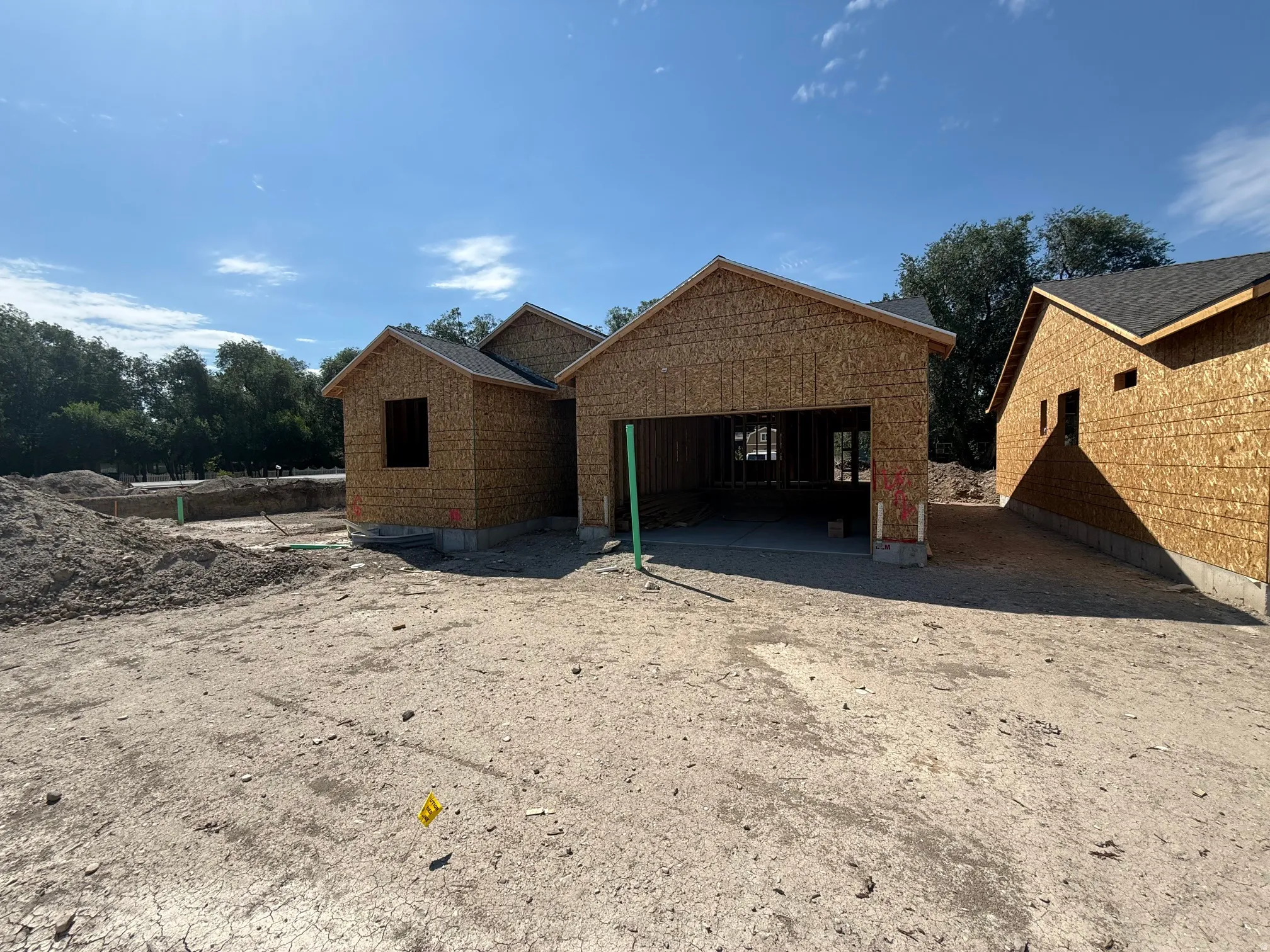 New construction framing featuring an attached garage, a window opening, and a partial foundation