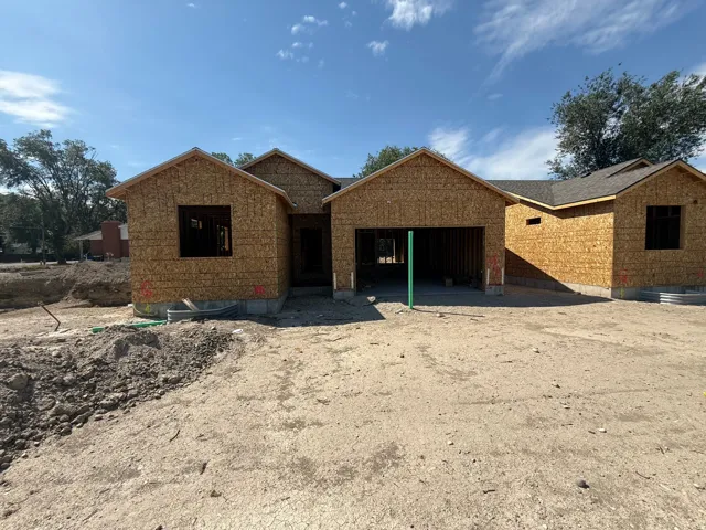 New construction residence with an unfinished exterior, featuring a visible roofline and an attached garage