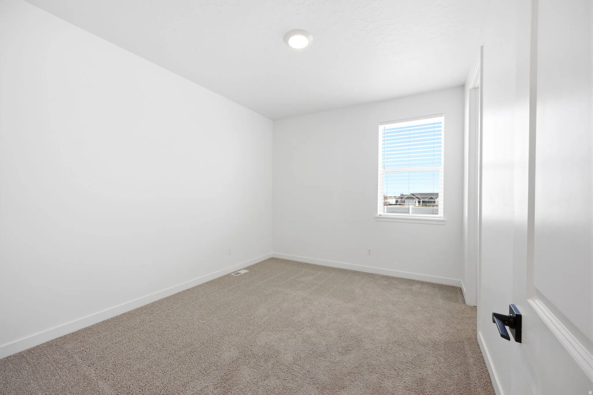 Carpeted room with white walls, white baseboards, and a single window with horizontal blinds